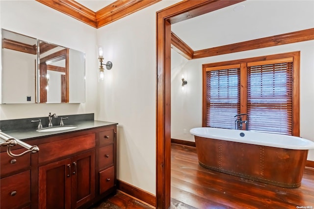 bathroom featuring hardwood / wood-style floors, vanity, ornamental molding, and a bath