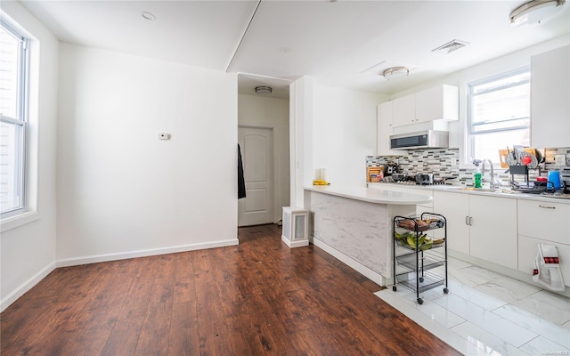 kitchen featuring a breakfast bar, dark hardwood / wood-style floors, tasteful backsplash, white cabinetry, and sink