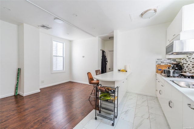 kitchen featuring tasteful backsplash, stovetop, and white cabinets