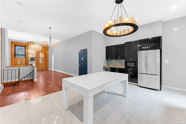 kitchen featuring black microwave, hanging light fixtures, stainless steel fridge, a chandelier, and light hardwood / wood-style floors