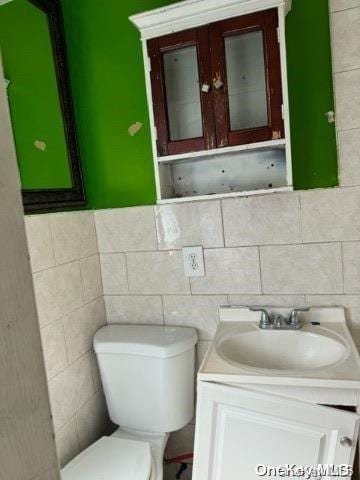 bathroom with vanity, toilet, and tile walls