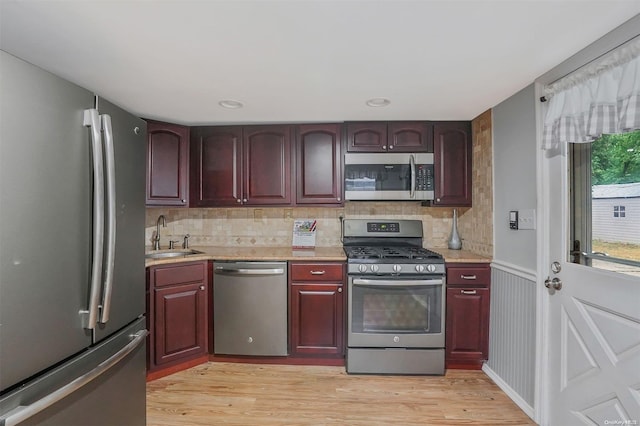 kitchen featuring appliances with stainless steel finishes, tasteful backsplash, light hardwood / wood-style flooring, and sink