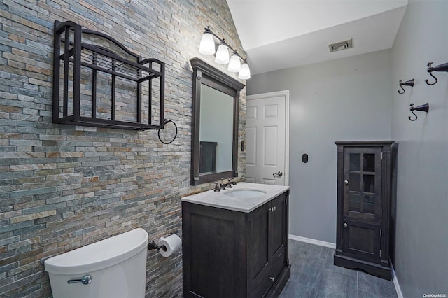 bathroom featuring vanity, vaulted ceiling, and toilet