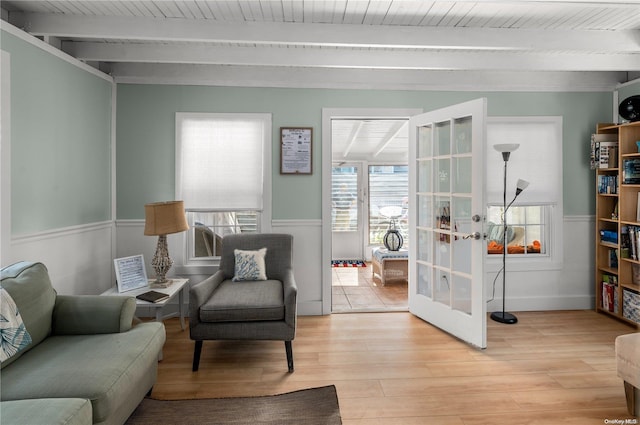 living area featuring beam ceiling, light wood-type flooring, french doors, and wooden ceiling