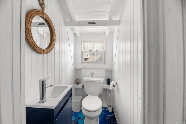 bathroom featuring vanity, toilet, and wood walls