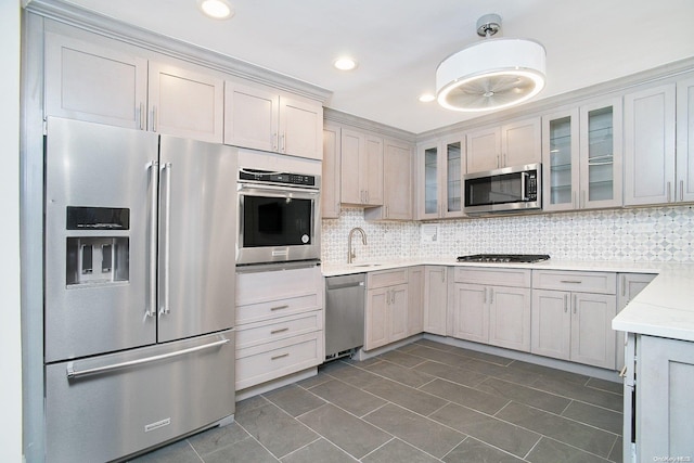 kitchen with light stone countertops, sink, dark tile patterned floors, backsplash, and appliances with stainless steel finishes