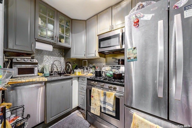 kitchen featuring tasteful backsplash, gray cabinetry, sink, and stainless steel appliances