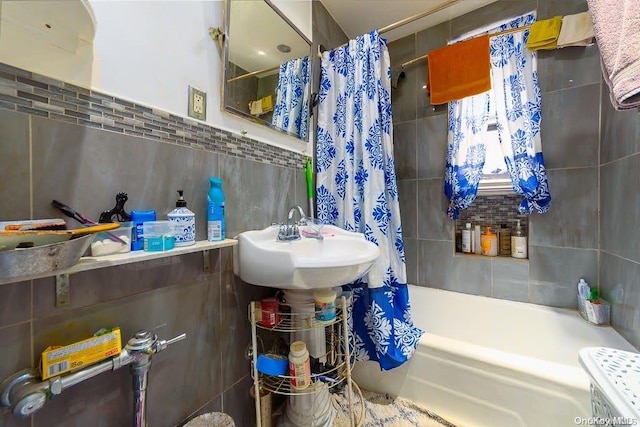 bathroom with shower / bath combo with shower curtain, sink, and tile walls