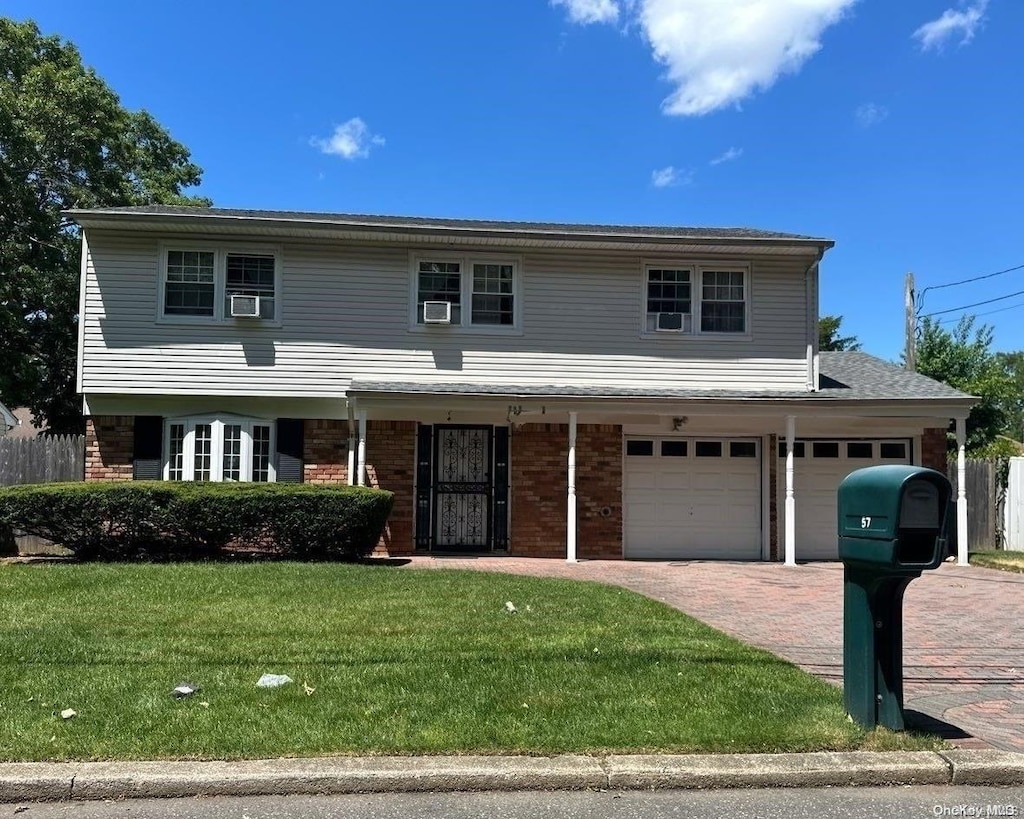 front of property featuring a front yard, a garage, and cooling unit