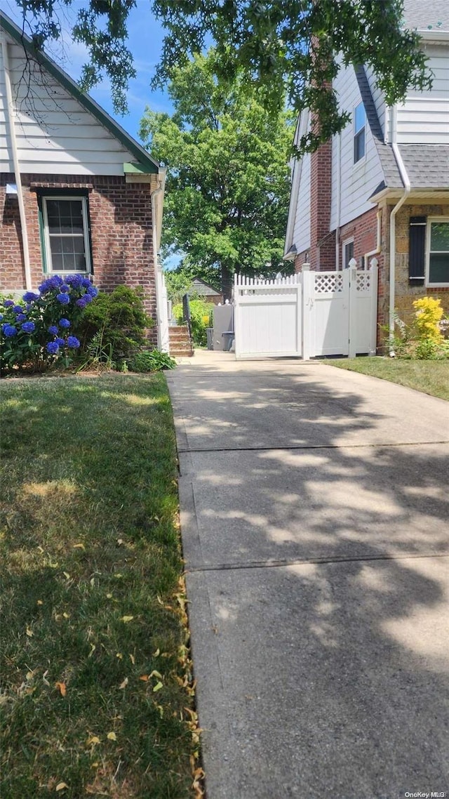 48-27 213th St, Bayside, NY 11364 - view of side of property with brick siding, driveway, and a gate