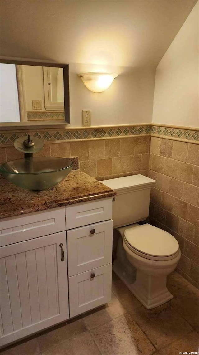 bathroom with vanity, toilet, and tile walls