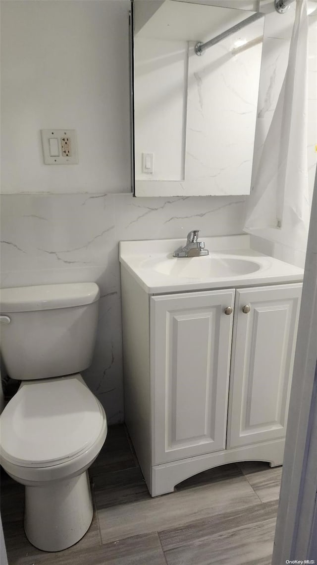 bathroom featuring vanity, tile walls, and toilet