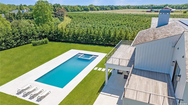 view of pool featuring a lawn, a patio area, and a rural view