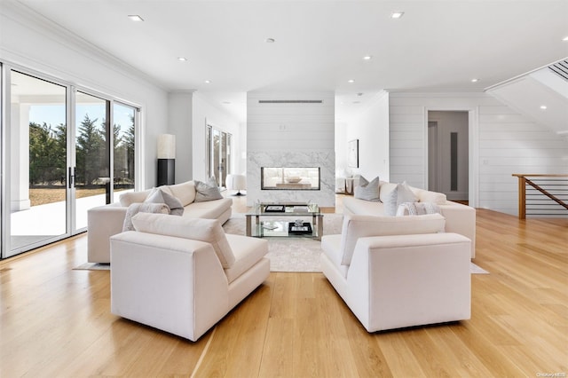 living room with light hardwood / wood-style floors, ornamental molding, and wood walls