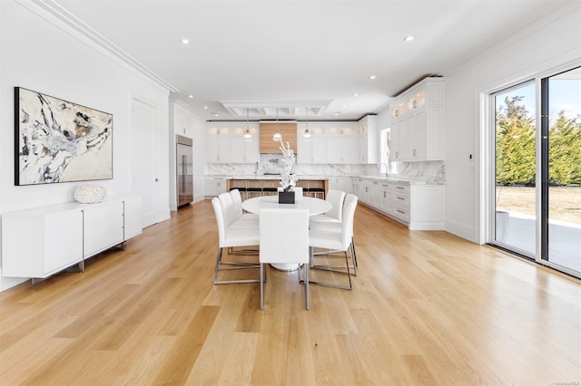 dining area featuring ornamental molding, sink, and light hardwood / wood-style flooring