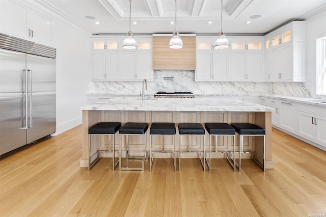 kitchen with an island with sink, stainless steel appliances, and light wood-type flooring