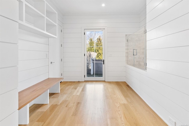 mudroom featuring light wood-type flooring, ornamental molding, and wooden walls