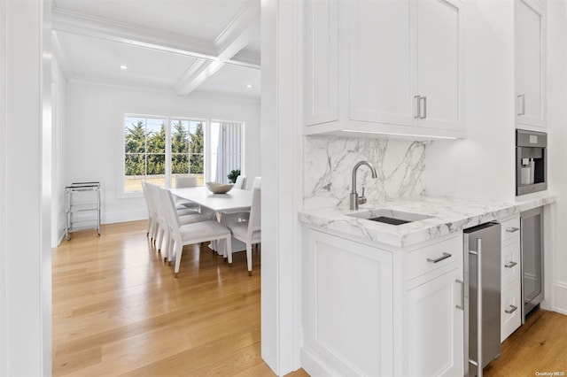 kitchen with white cabinets, light wood-type flooring, sink, and coffered ceiling