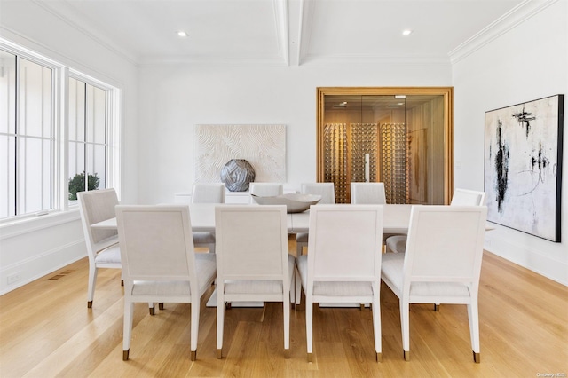 dining room featuring beam ceiling, light hardwood / wood-style flooring, and ornamental molding