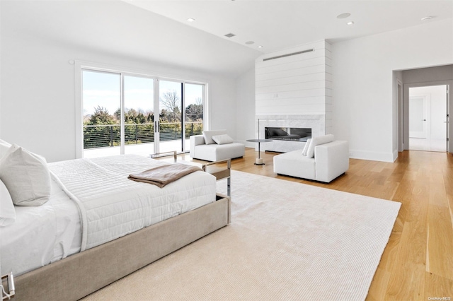 bedroom featuring a fireplace, light hardwood / wood-style floors, and vaulted ceiling