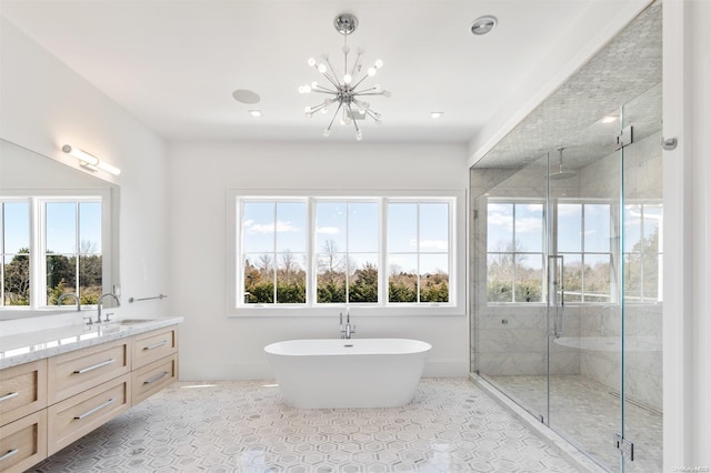 bathroom featuring independent shower and bath, a chandelier, vanity, and a healthy amount of sunlight