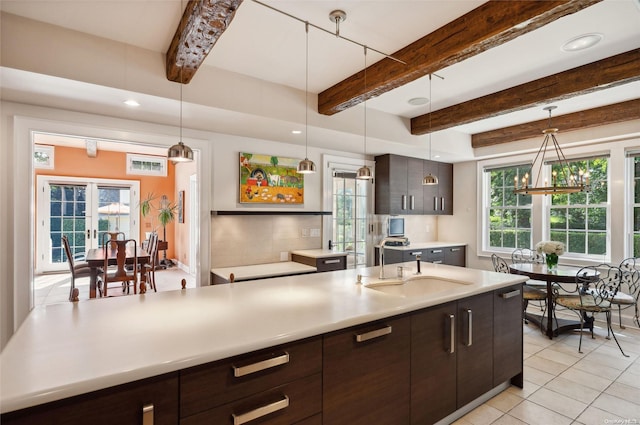 kitchen with pendant lighting, french doors, sink, beamed ceiling, and dark brown cabinets