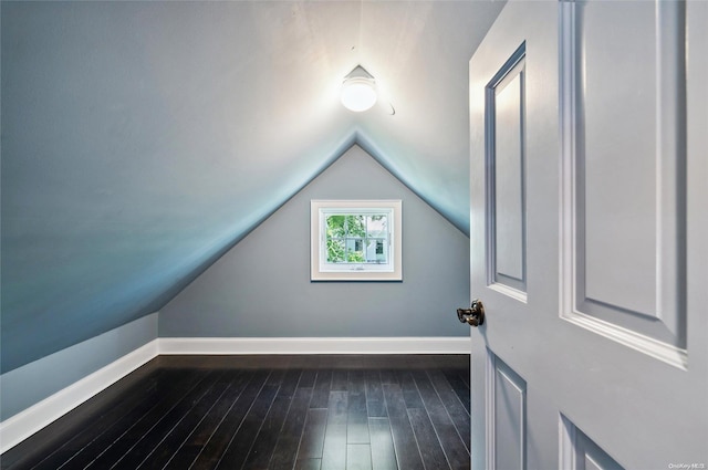 additional living space featuring dark wood-type flooring and vaulted ceiling