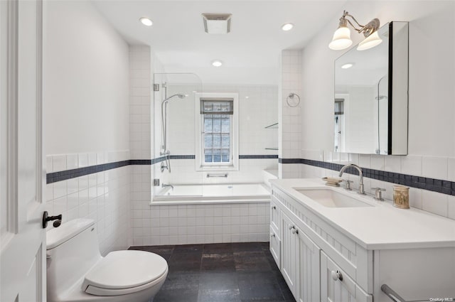 full bathroom with vanity, tiled shower / bath combo, tile walls, a notable chandelier, and toilet