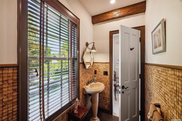 bathroom featuring beamed ceiling, tile patterned floors, and tile walls