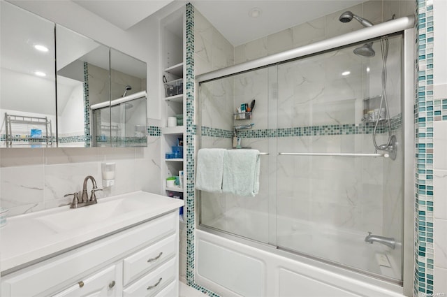 bathroom featuring vanity, shower / bath combination with glass door, and backsplash