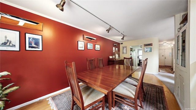 dining space with light wood-type flooring, track lighting, and crown molding