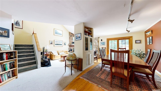 dining room featuring hardwood / wood-style flooring, rail lighting, and vaulted ceiling