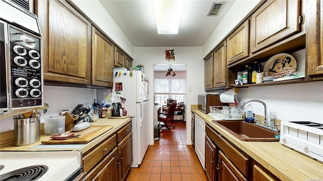 kitchen featuring white appliances, dark tile patterned floors, and sink