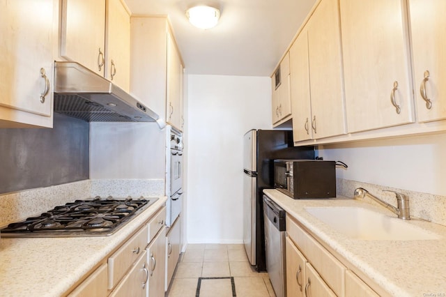 kitchen with light tile patterned flooring, stainless steel appliances, light brown cabinetry, and sink