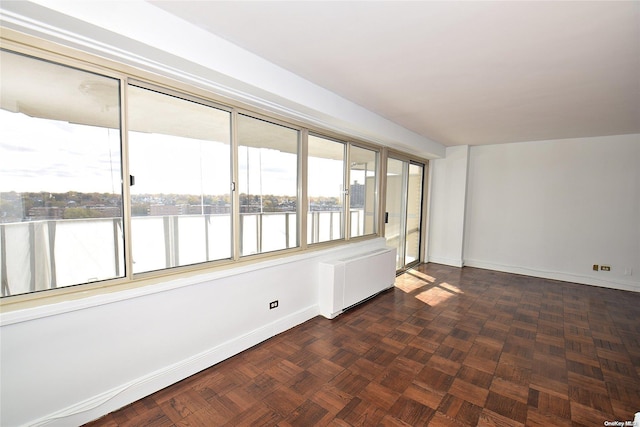 unfurnished room featuring radiator, dark parquet flooring, and a water view