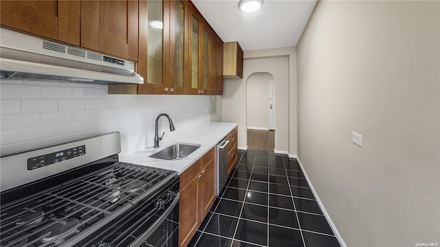 kitchen with backsplash, exhaust hood, sink, dark tile patterned floors, and appliances with stainless steel finishes