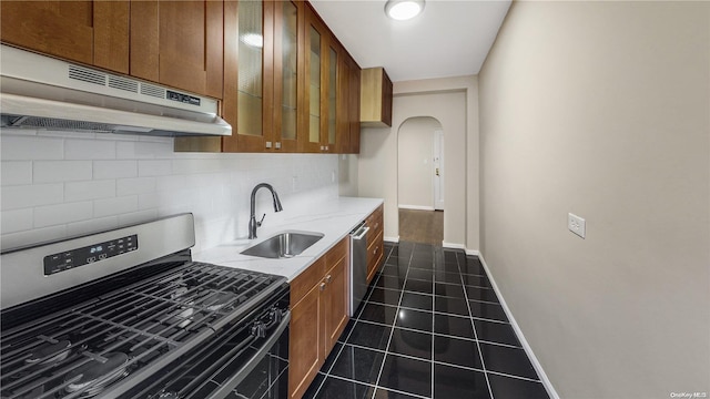 35-38 75th St Unit 4C, Jackson Heights, NY 11372 - kitchen with stainless steel appliances, under cabinet range hood, arched walkways, decorative backsplash, and dark tile patterned floors