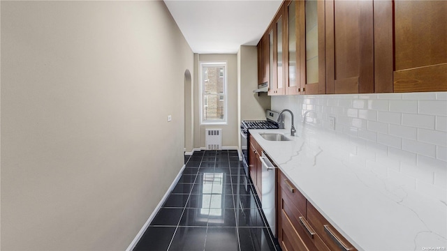 kitchen with light stone countertops, range hood, decorative backsplash, dark tile patterned flooring, and appliances with stainless steel finishes