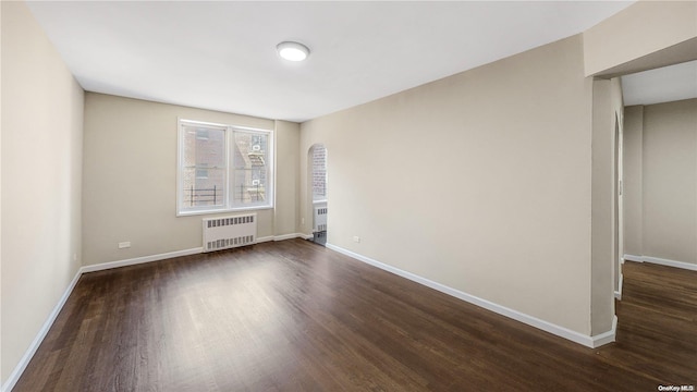 empty room with radiator heating unit and dark hardwood / wood-style floors