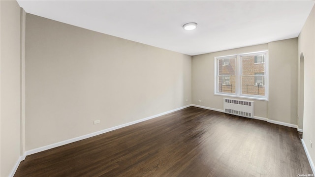 spare room with radiator and dark hardwood / wood-style floors