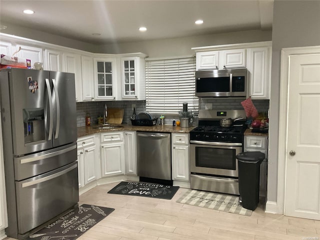 kitchen with decorative backsplash, sink, white cabinets, and stainless steel appliances