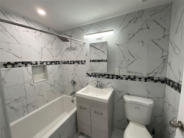 full bathroom with vanity, tiled shower / bath combo, toilet, and tile walls