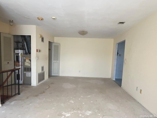 unfurnished room with concrete floors and water heater