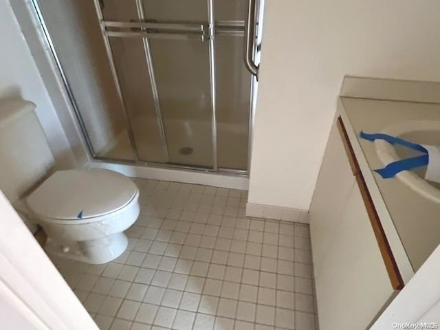 bathroom with tile patterned floors, a shower with door, vanity, and toilet