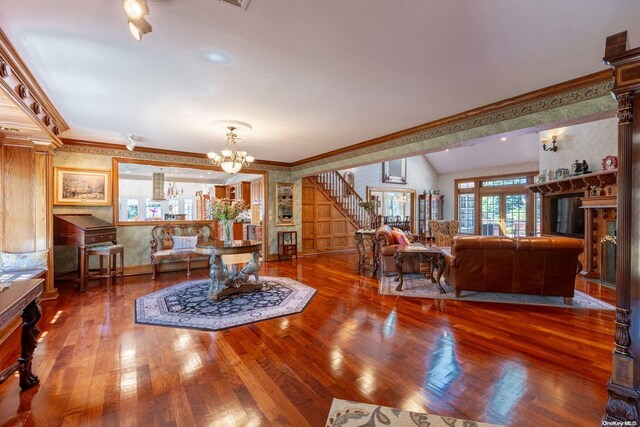 living room featuring wood-type flooring, crown molding, and a chandelier