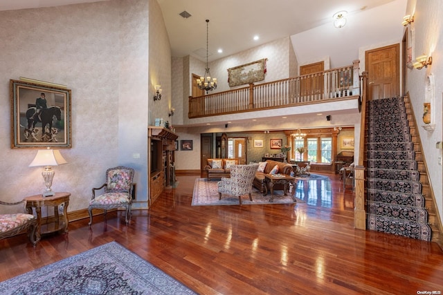 living room with an inviting chandelier, a high ceiling, and hardwood / wood-style flooring