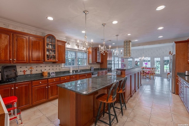 kitchen featuring stainless steel fridge, backsplash, ventilation hood, a kitchen island, and hanging light fixtures