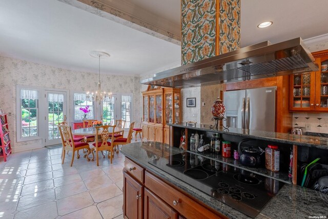 kitchen with black electric cooktop, wall chimney exhaust hood, dark stone counters, and stainless steel refrigerator with ice dispenser