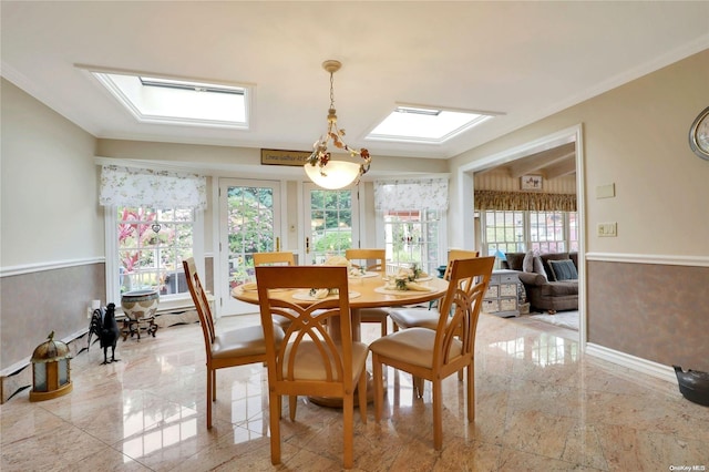 dining space featuring vaulted ceiling with skylight and ornamental molding