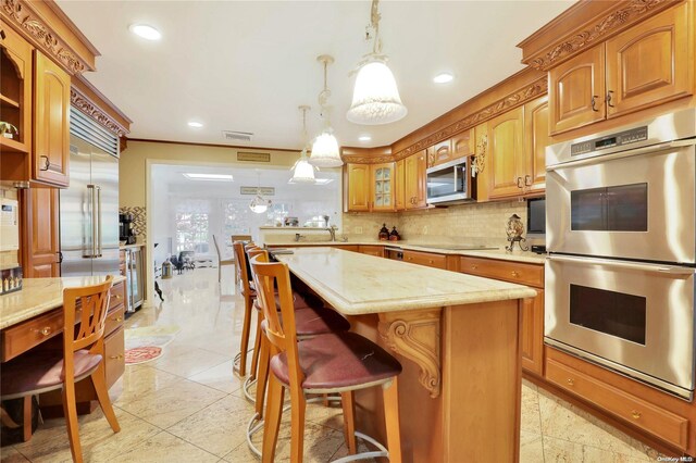 kitchen featuring hanging light fixtures, stainless steel appliances, a breakfast bar area, decorative backsplash, and a kitchen island